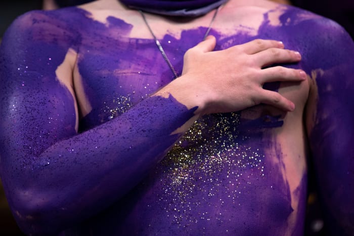 A Bowling Green Purples student puts his hand over his purple-painted heart during the national anthem at a 2021 basketball game.